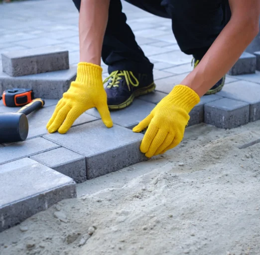 Person-paving-with-yellow-gloves-and-tools-scaled