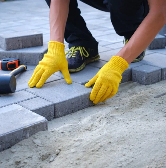 Person-paving-with-yellow-gloves-and-tools-scaled