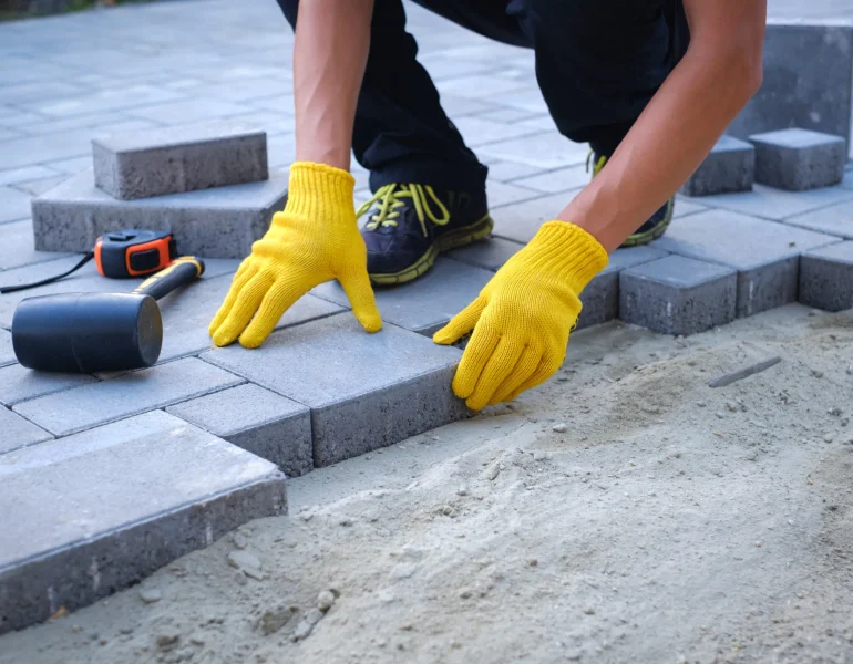 Person-paving-with-yellow-gloves-and-tools-scaled